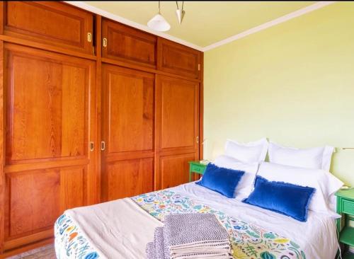 a bedroom with a bed with blue pillows and wooden cabinets at Sunset over the sea in Playa de las Americas