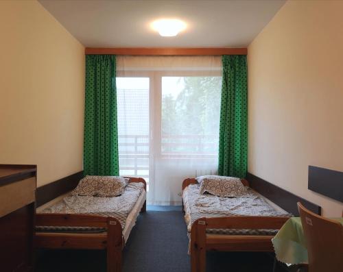 a room with two beds and a window with green curtains at Ośrodek Szpulki in Zakopane