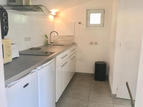 eine Küche mit weißen Schränken, einem Waschbecken und einem Fenster in der Unterkunft Maisonnette studio Arcachon 300m plage in Arcachon