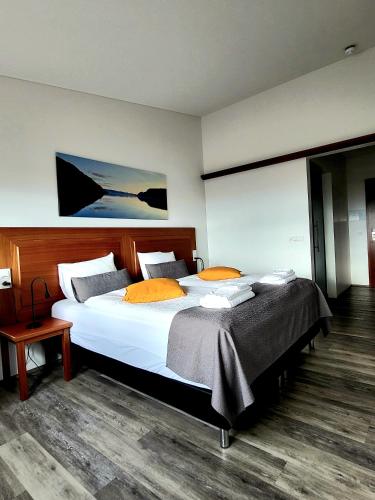 a bedroom with a large white bed with orange pillows at Hótel Flókalundur in Brjánslækur