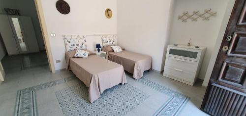 a room with two beds and a television and a door at A 2 passi dal mare - grazioso trilocale a Locri in Locri