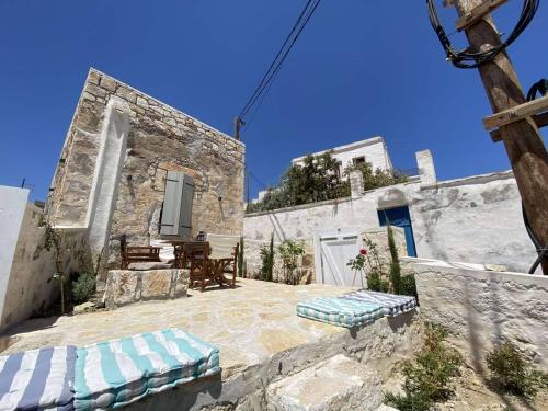 un edificio de piedra con un patio con 2 bancos en Fournos, en Kimolos