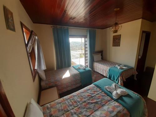 a hotel room with two beds and a window at Vilarejo da Esperanza in Campos do Jordão