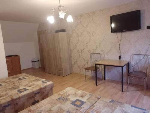 a living room with a table and chairs and a television at Penzion Anna in Hrabušice