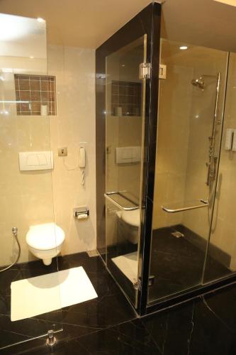 a bathroom with a toilet and a glass shower at The Regenza By Tunga in Navi Mumbai