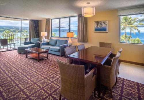 a living room with a table and chairs at Hilo Hawaiian Hotel, Trademark Collection by Wyndham in Hilo