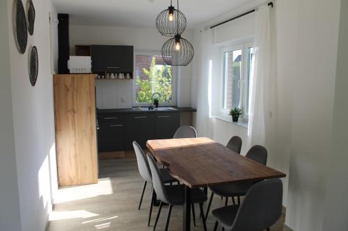 cocina y comedor con mesa de madera y sillas en Ferienhaus am Seedeich, en Emden