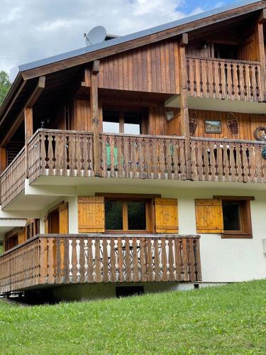 a house with a wooden deck on the side of it at Marmotte du Jaillet Cosy and charmant appartement in Demi-Quartier