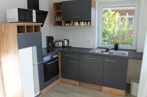 a kitchen with black cabinets and a sink at Ferienhaus am Seedeich in Emden