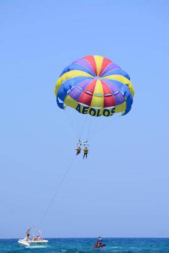a person on a parachute over the ocean with a boat at Aeolos Beach Resort in Malia