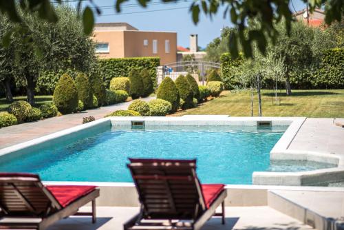 two chairs sitting next to a swimming pool at Sunset Garden apartment with private pool in Vrsi