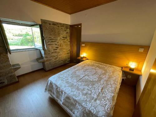 een slaapkamer met een bed en een raam bij Recantos da Montanha in Candal