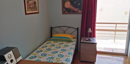 um pequeno quarto com uma cama e uma janela em Ομορφο διαμερισμα με μεγαλες βεραντες em Atenas