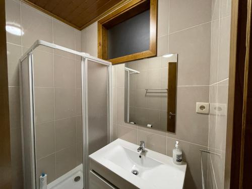 een badkamer met een wastafel, een douche en een spiegel bij Recantos da Montanha in Candal