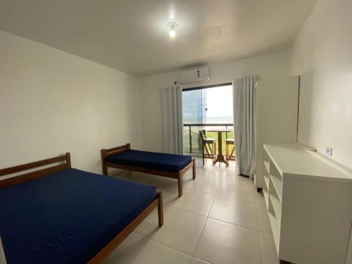 a bedroom with a bed and a table and a window at Condominio Boa Vista in Pontal do Paraná