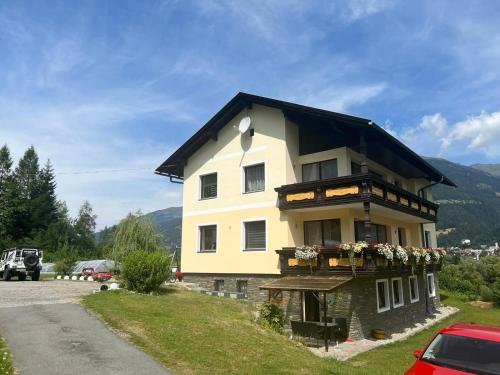 a building with a black roof and flowers on it at Schöne Ferienwohnung, Familienfreundlich 130m2 in Greifenburg