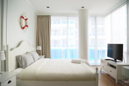 een witte slaapkamer met een bed en een televisie bij My Resort Hua Hin A303 in Hua Hin