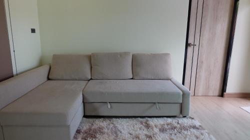 un sofá sentado en una sala de estar junto a una puerta en The Backyard Homestay, en Pak Chong