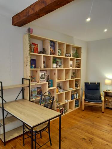 a room with a table and a chair and bookshelves at L'Oustal des amis in Belcaire