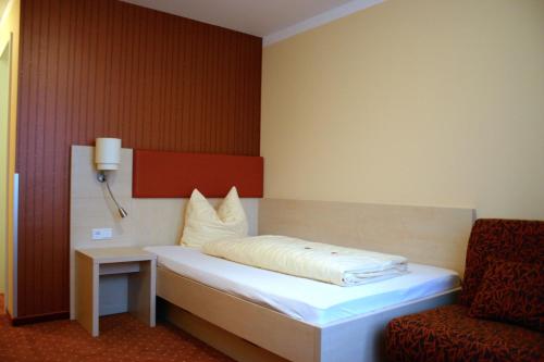 Bett in einem Zimmer mit einem Stuhl und einem Bett sidx sidx sidx sidx in der Unterkunft Hotel Petzengarten in Nürnberg