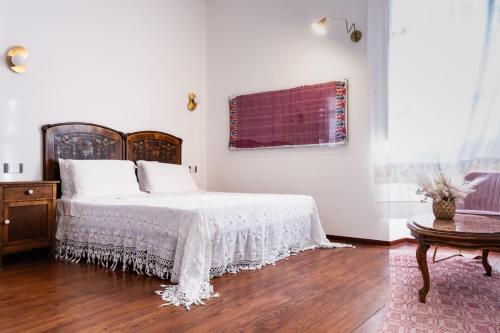 a white bedroom with a bed and a wooden floor at Dimora Ferraris in Càbras