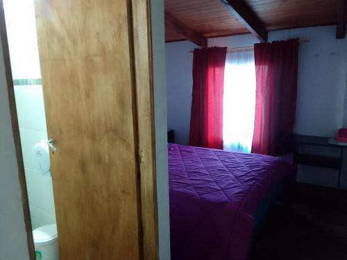 1 dormitorio con cama morada y ventana en Ushuaia de las Nieves B&B en Ushuaia