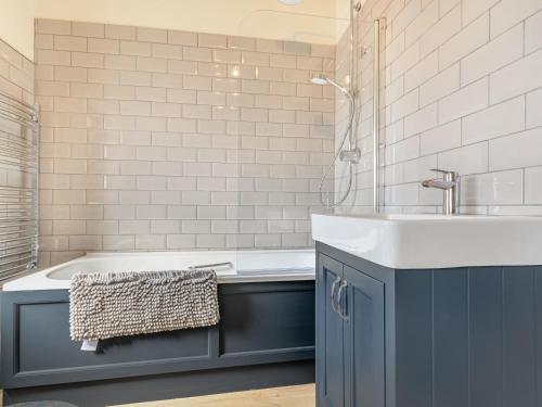 a bathroom with a blue sink and a tub at The Paddock in Shipston on Stour