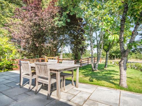 a wooden table and chairs on a patio with trees at The Paddock in Shipston on Stour