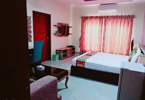 um quarto com uma cama, uma cadeira e uma janela em Hotel Versa Appartments lodges Gulberg3 em Lahore