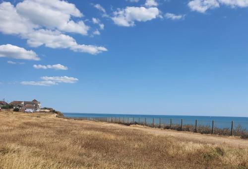 a field with a fence and the ocean at Four Seasons by the Sea in Peacehaven