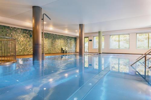 a swimming pool in a building with a swimming pool at Grand Hotel Opduin in De Koog