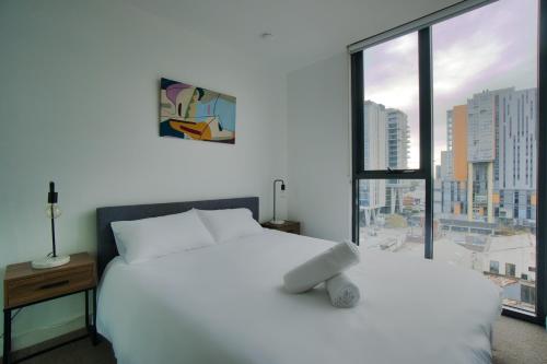 Cette chambre comprend un lit blanc et une grande fenêtre. dans l'établissement Luxury 2 Bedroom Apartment - Adelaide CBD, à Adélaïde