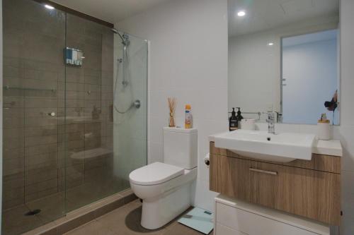 uma casa de banho com um WC, um chuveiro e um lavatório. em Luxury 2 Bedroom Apartment - Adelaide CBD em Adelaide