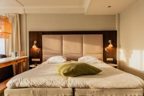a bedroom with a large bed with a pillow on it at Grand Hotel Opduin in De Koog