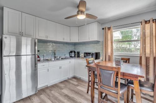 a kitchen with white cabinets and a table and a refrigerator at Downtown Single Family Modern Bungalow close to beaches and dining home in Sarasota