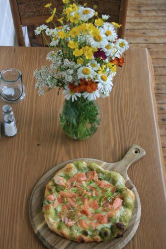 a pizza on a table next to a vase of flowers at Auberge Presbytere Mont Lac-Vert in Hébertville