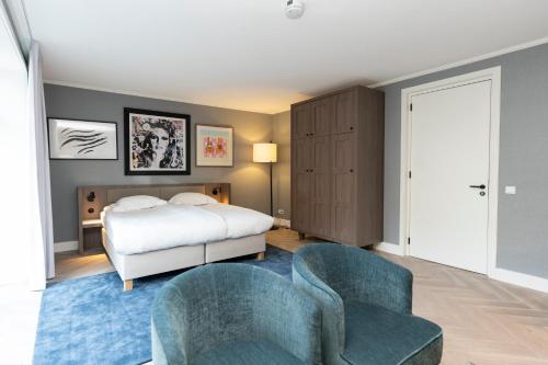 a bedroom with a bed and two chairs at Grand Hotel Opduin in De Koog
