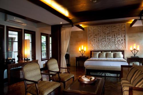 1 dormitorio con cama, sillas y mesa en Villa Amani, en Tanah Lot