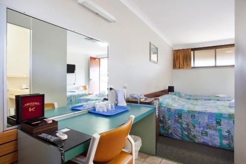 a room with a desk and a bed and a mirror at Vale Hotel in Townsville