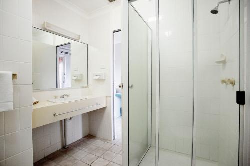 a bathroom with a glass shower and a sink at Vale Hotel in Townsville