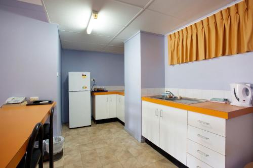 a kitchen with a refrigerator, microwave, sink and a table at Vale Hotel in Townsville