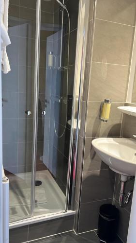 a shower with a glass door next to a sink at Palm Premium Hotel & Apartments in Düsseldorf