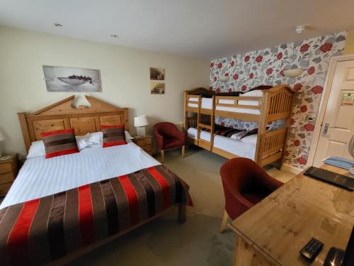 a bedroom with two beds and a desk and a table at The Royal Inn in St Austell