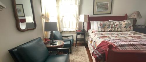 a bedroom with a bed and a chair and a table at Wayside Inn Bed and Breakfast in Ellicott City