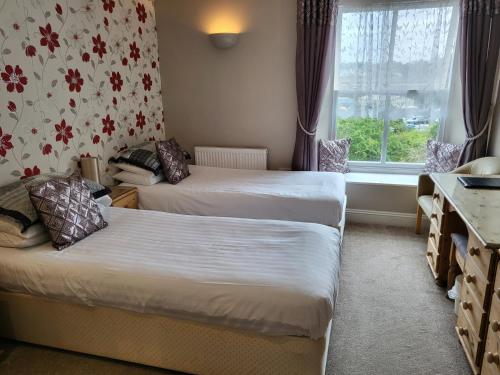 a hotel room with two beds and a window at The Royal Inn in St Austell