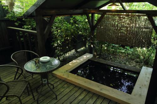 a wooden deck with a table and a pond at Shinwaen in Aso
