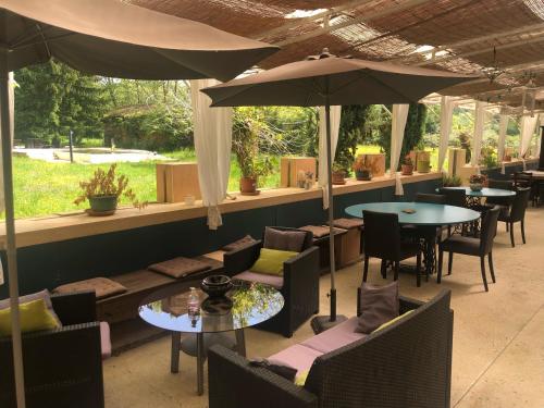 un restaurant avec des tables, des chaises et des parasols dans l'établissement Logis Hôtel Le Clos Pité, à Préchacq-les-Bains