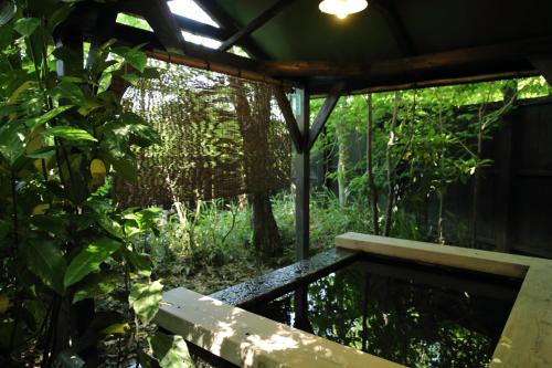 a screened in porch with a bench in a garden at Shinwaen in Aso