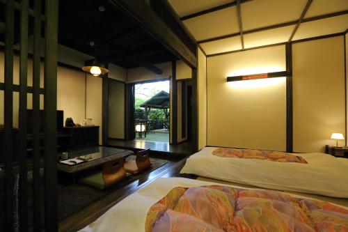 a bedroom with two beds and a desk and a window at Shinwaen in Aso