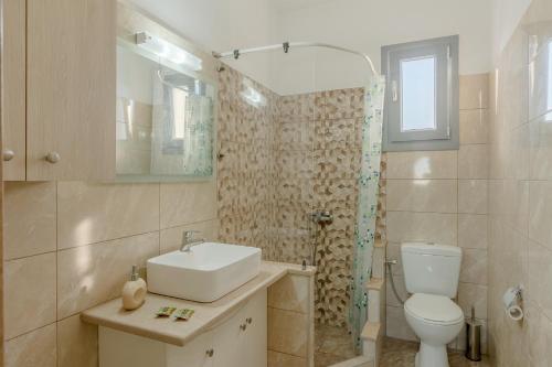 een badkamer met een toilet, een wastafel en een douche bij House on the black beach with sea view and parking in Agios Georgios Thalassiti